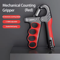 A red and black mechanical counting hand grip with a spring-loaded open mechanism, shown standing upright on a dark surface against a dark gray background. White and red text on the left reads 'Mechanical Counting Gripper (Red)' with feature callouts including 'LCE electronic counting display,' '5-100KG adjustable,' and 'Double Bold Spring. - RED VARIANT