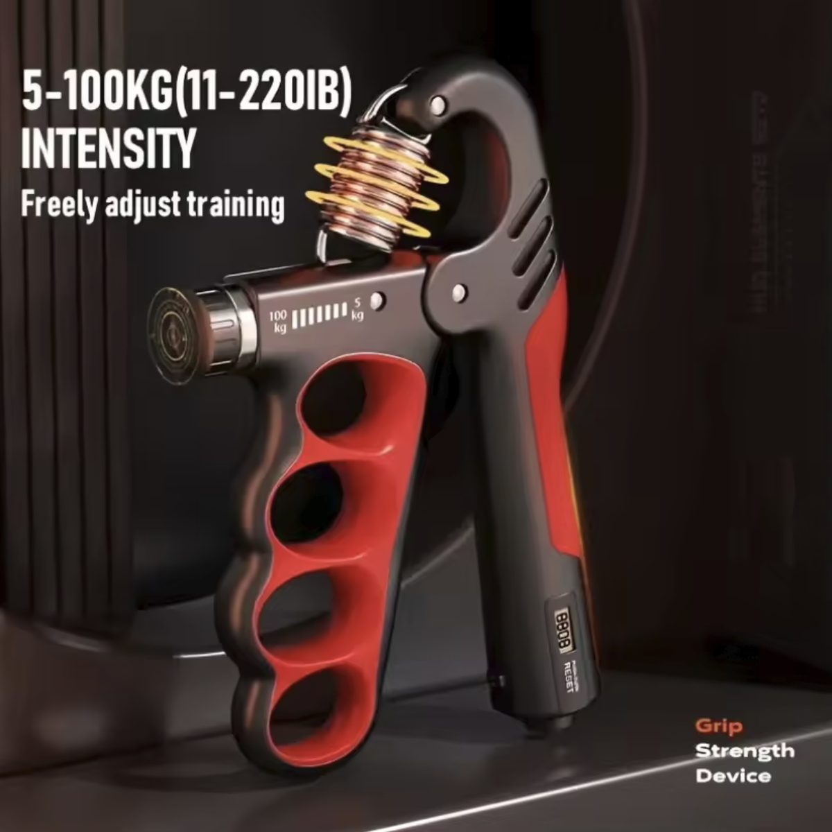 A hand grip strengthener shown upright on a dark surface with overlaid text reading '5-100KG(11-220IB) INTENSITY Freely adjust training' and 'Grip Strength Device.' The product is primarily black and red with a metallic spring and small silver adjustment detail.